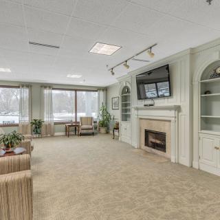 A spacious living room featuring a fireplace and television, with comfortable seating and large windows.