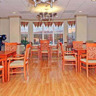 A brightly decorated dining area with orange chairs and wooden flooring.