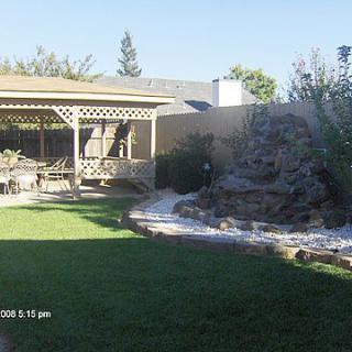 A backyard with a pergola, green lawn, and garden landscaping.