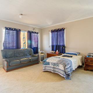 A cozy bedroom featuring a bed, sofa, and windows with curtains.