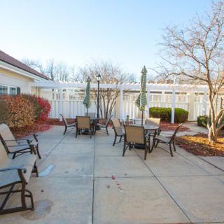 An outdoor patio with chairs and tables set under a clear blue sky.