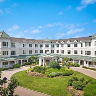 A large residential building with a well-maintained garden and clear blue sky.
