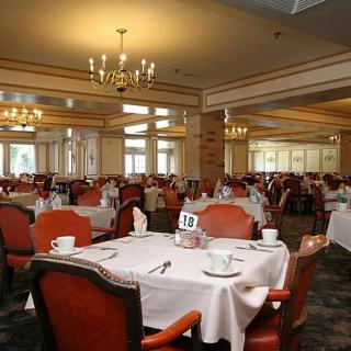 A formal dining room with elegantly set tables and chandeliers.