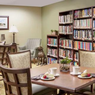 A cozy library reading area with bookshelves, a table, and chairs.
