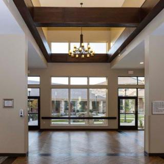 A spacious lobby area with a chandelier and large windows letting in natural light.