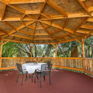 A cozy wooden gazebo featuring a round table and chairs, perfect for enjoying the outdoors.