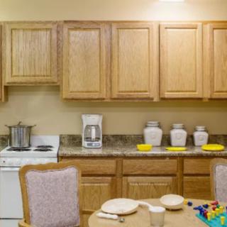 A cozy kitchen with wooden cabinets, a countertop featuring kitchen appliances, and a table set for dining.