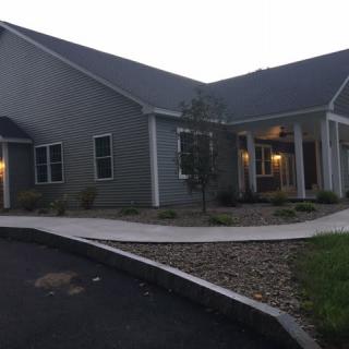 A single-story residential building with a sloped roof and landscaped front yard.