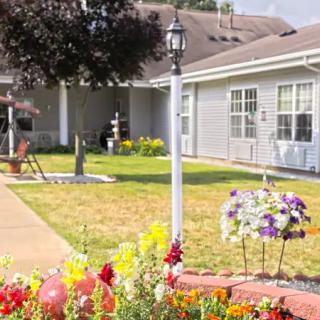 A well-maintained garden with colorful flowers and a lamp post in front of a house.