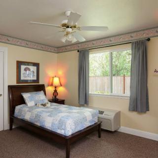 A cozy bedroom with a single bed, bedside lamp, and a window with curtains.