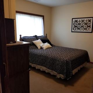 A cozy bedroom with a neatly made bed, adorned with decorative pillows and art on the wall.