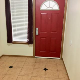 A simple entryway featuring a red door and tiled flooring.