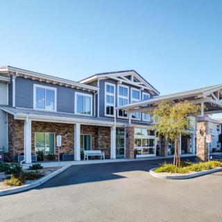 A modern two-story building with a prominent entrance and clear blue sky.