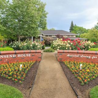 A beautifully landscaped garden with a pathway leading to a house, surrounded by colorful flowers and greenery.
