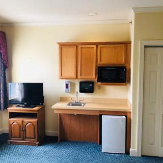 A small kitchenette area in a hotel room featuring a TV, microwave, sink, and refrigerator.