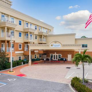 A multi-story building with a grand entrance, featuring an American flag and surrounded by palm trees.