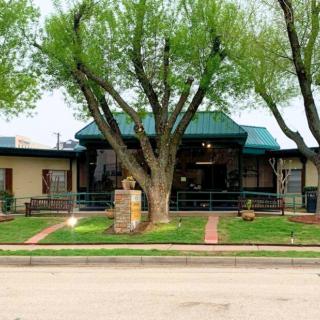 A quaint building with a green roof surrounded by trees and a well-maintained lawn.