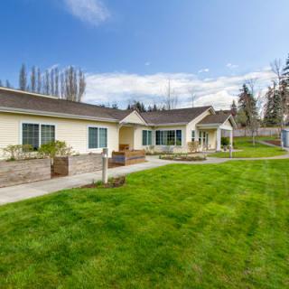 A modern house with a well-maintained lawn and landscaping under a clear blue sky.