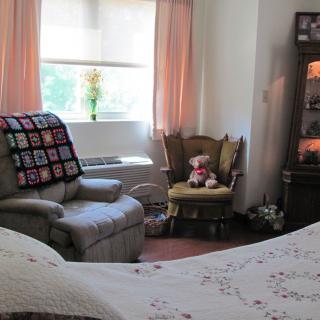A cozy living room with a recliner, rocking chair, and sunlight streaming through the window.