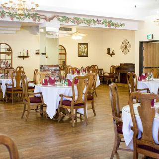 An elegantly set restaurant dining room with round tables and wooden chairs.