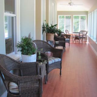 A bright sunroom with wicker chairs, indoor plants, and large windows allowing natural light to fill the space.