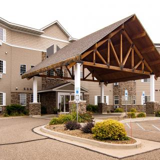A welcoming entrance to a modern building with a wooden canopy and surrounding landscaping.