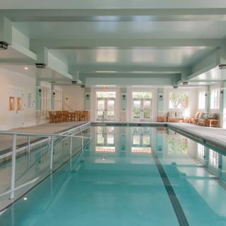 A spacious indoor swimming pool with clean, calm water and ample natural light.