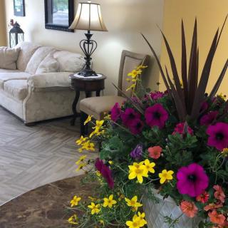 A cozy lobby area featuring a plush sofa, side table with a lamp, and a vibrant floral arrangement.