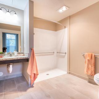 A modern bathroom featuring a walk-in shower and stylish vanity with warm lighting.