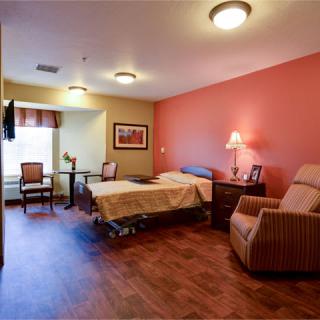 A cozy hospital room with a single bed, desk, and comfortable chair.