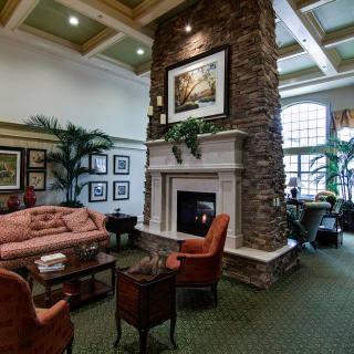 A cozy and elegantly designed living room featuring a stone fireplace, artwork, and comfortable seating.