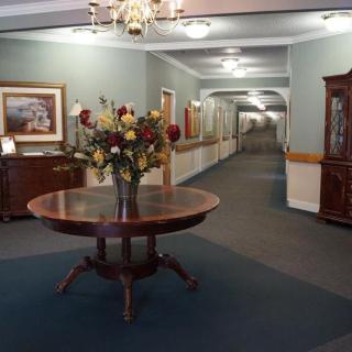 A hallway with elegant decor featuring a round table and a vase of flowers.