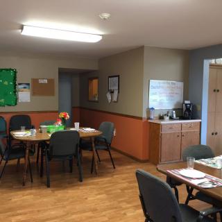 An office meeting room with tables, chairs, a notice board, and a whiteboard.