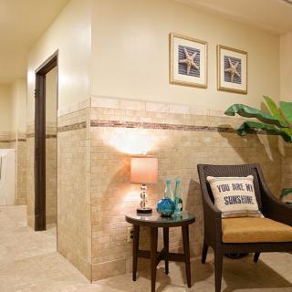 A cozy lobby area with an armchair, side table, lamp, and decorative elements.