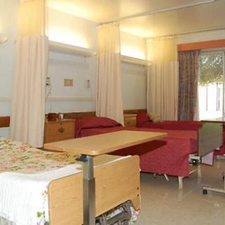 A hospital room with multiple beds and curtains for patient privacy.