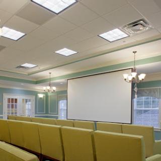 A well-lit meeting room featuring comfortable seating and a large presentation screen.