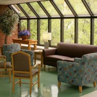 A cozy lounge area with ample natural light from large windows, featuring a variety of seating options and decorative plants.