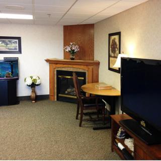 A cozy living room featuring a television, fireplace, table with chairs, and decorative elements.
