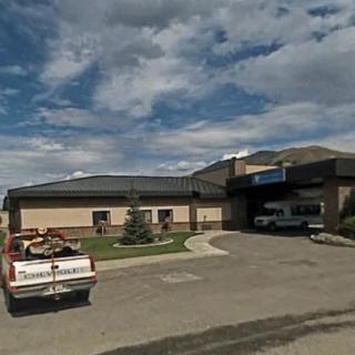 A building with a parking lot, featuring a truck and a cloudy sky.