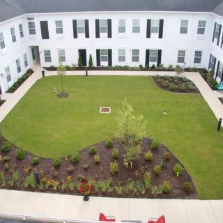 Aerial view of a courtyard with landscaped gardens surrounded by a two-story building.