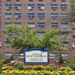 A brick building with a prominent sign and landscaping including trees and flowers.