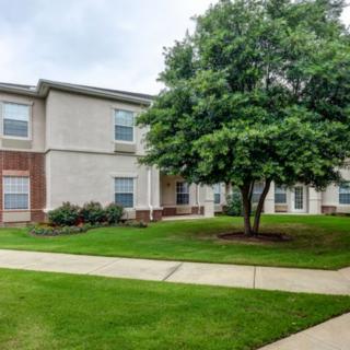 A residential apartment building with a well-maintained lawn and pathway.