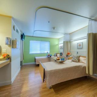 A clean and organized hospital room with two beds separated by a curtain.