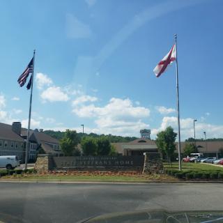 A view of flags representing the United States and Alabama, set against a clear blue sky.