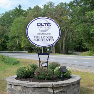 A landscaped roadside sign for DLTC The Landscape Care Company.
