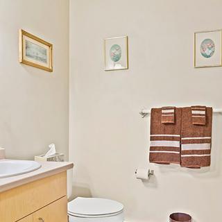 A neatly arranged bathroom featuring a toilet, sink, and decorative towels with framed artwork on the walls.