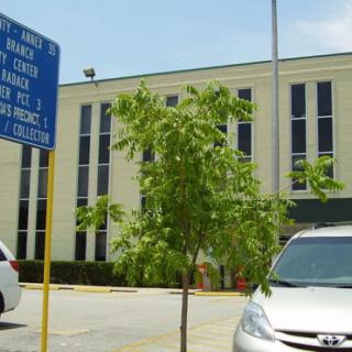 A parking lot in front of a modern building with cars and a blue sign.