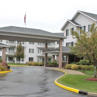 A view of a residential building with a covered entrance and landscaped driveway.