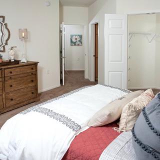 A cozy bedroom with a neatly made bed, dresser, and wall decor.