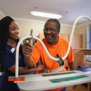 A healthcare professional assists an elderly man during a physical therapy session, fostering positive interaction and rehabilitation.